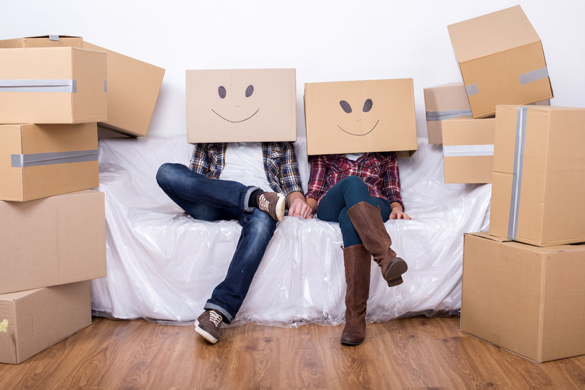 34166160 - couple with cardboard boxes on their heads with smiley face are sitting on floor after the moving house.
